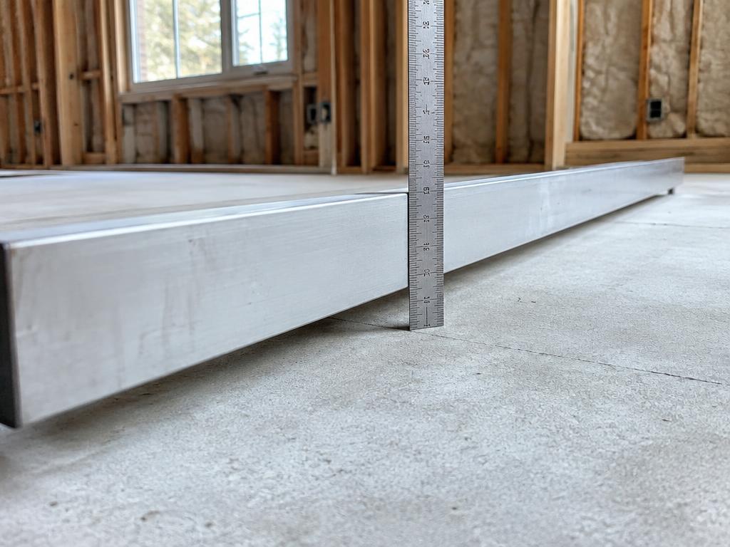 Measuring concrete subfloor flatness with a long straightedge before flooring installation.