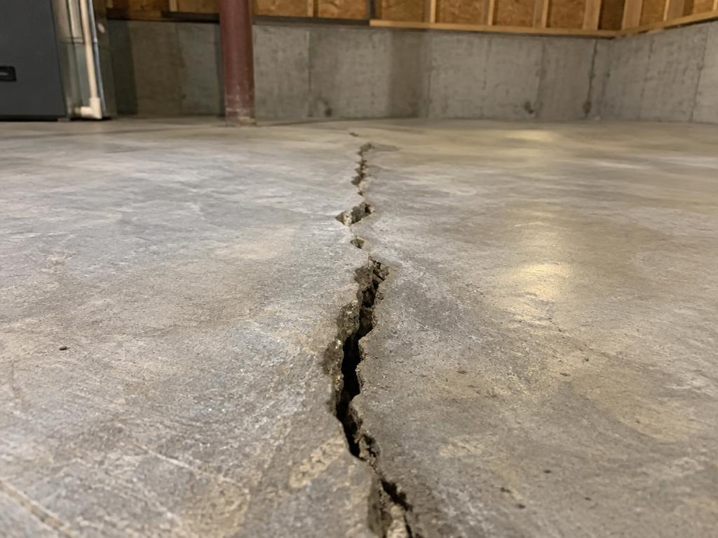 A crack with vertical displacement can indicate slab movement. Surface patching alone may not address the underlying cause.